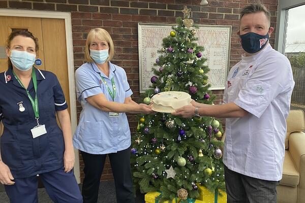 Mosimann’s chef Nick Hebditch and Daniel Thorpe present a cake to Oakhaven nurses, Suzanne Jones and Jane Leonard, to thank the team for their hard work and celebrate 2020 Year of the Nurse.”