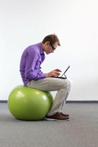 man at laptop sitting on inflatable ball